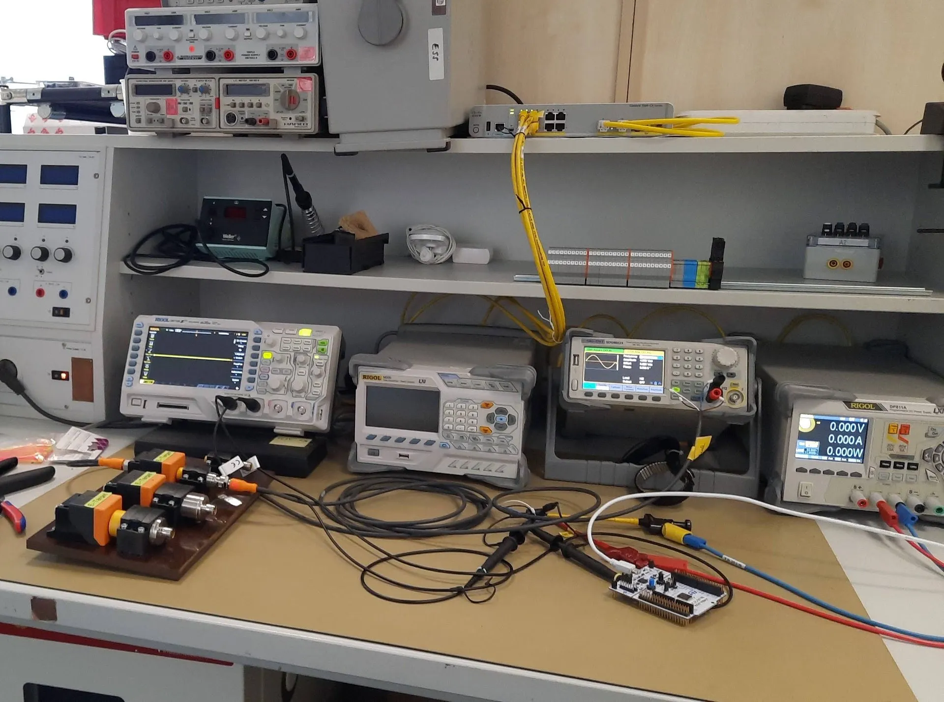 Elektronik-Messplatz mit Oszilloskop, Signalgenerator, Labornetzteil und Prüfling auf der Werkbank